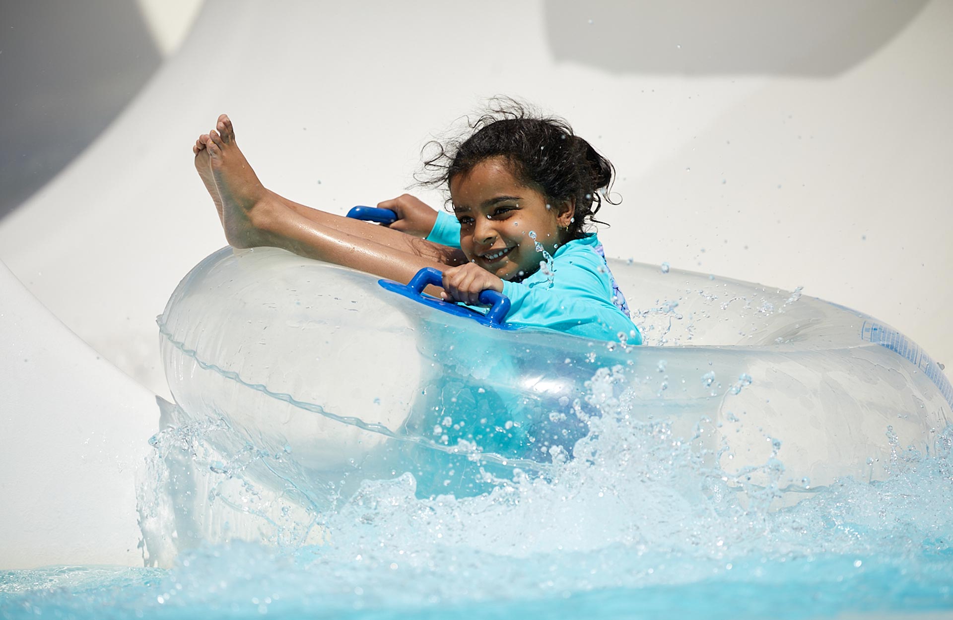 young Hispanic girl on floating tub going down water slide