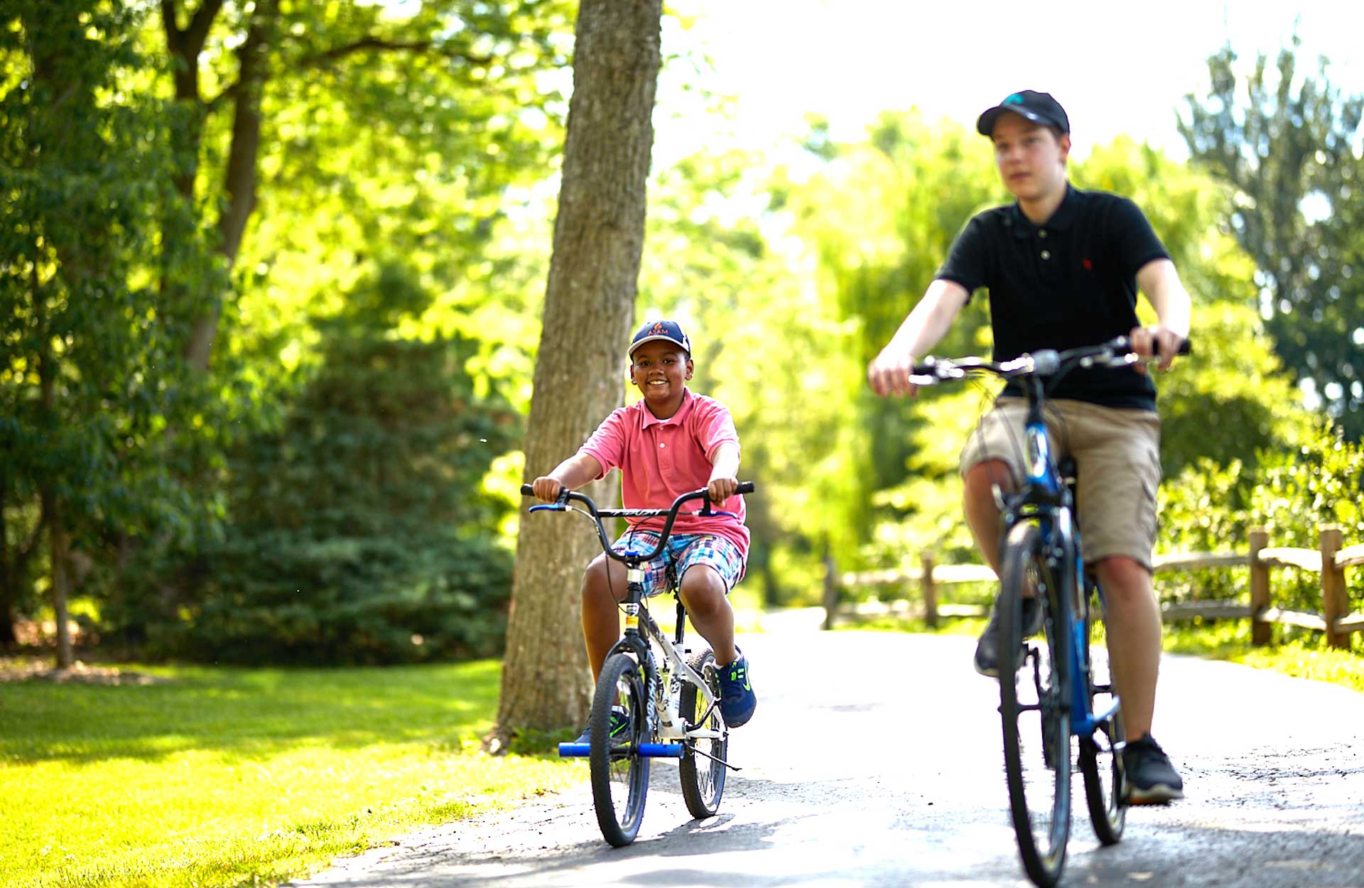 young African American and teenage white boy riding bikes together on bike path