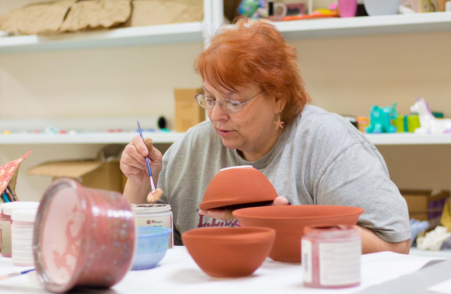 middle-aged white woman painting pottery in art program middle-aged white woman painting pottery in art program