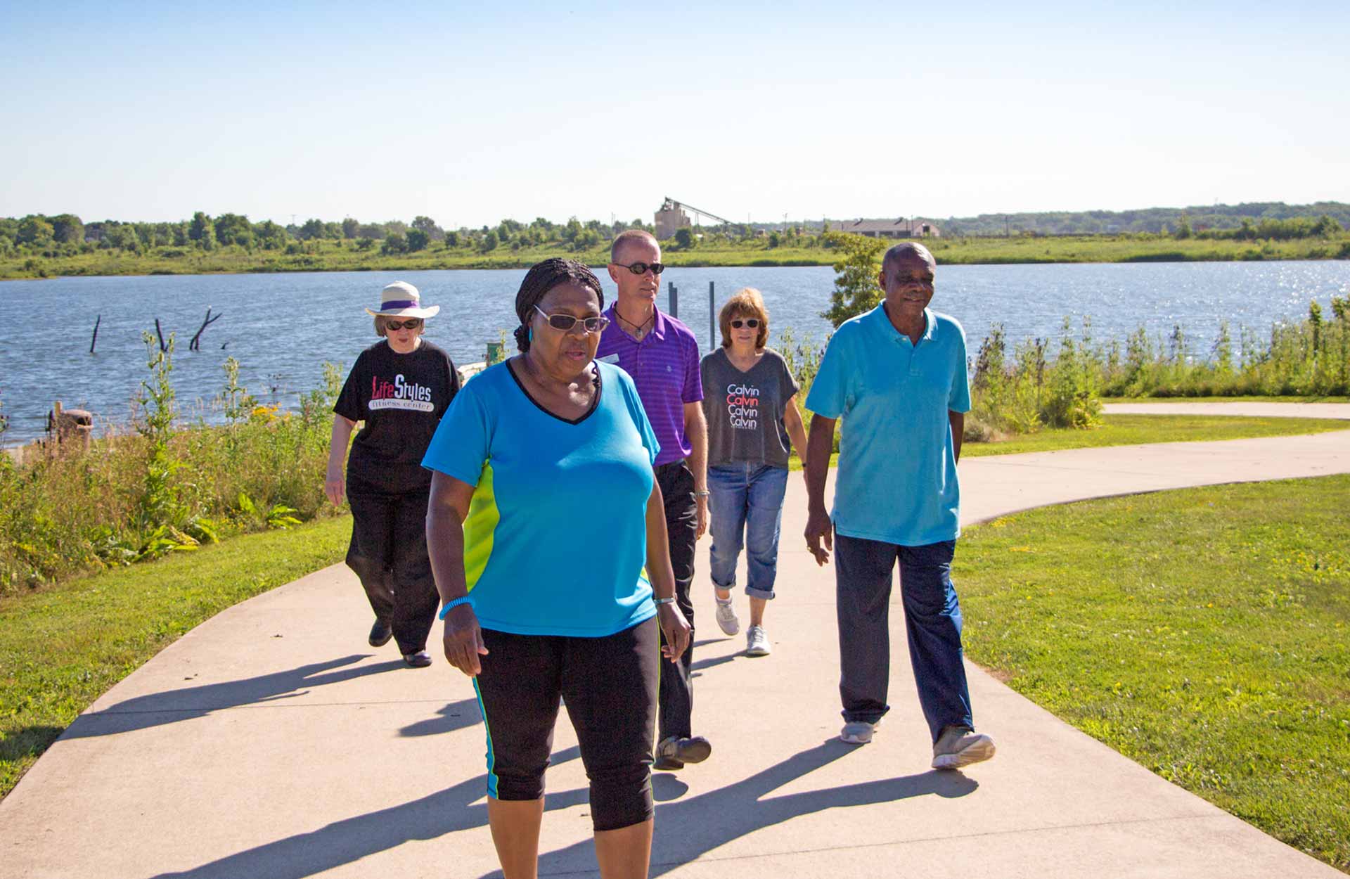 group of elderly adults on walking path next to lake group of elderly adults on walking path next to lake